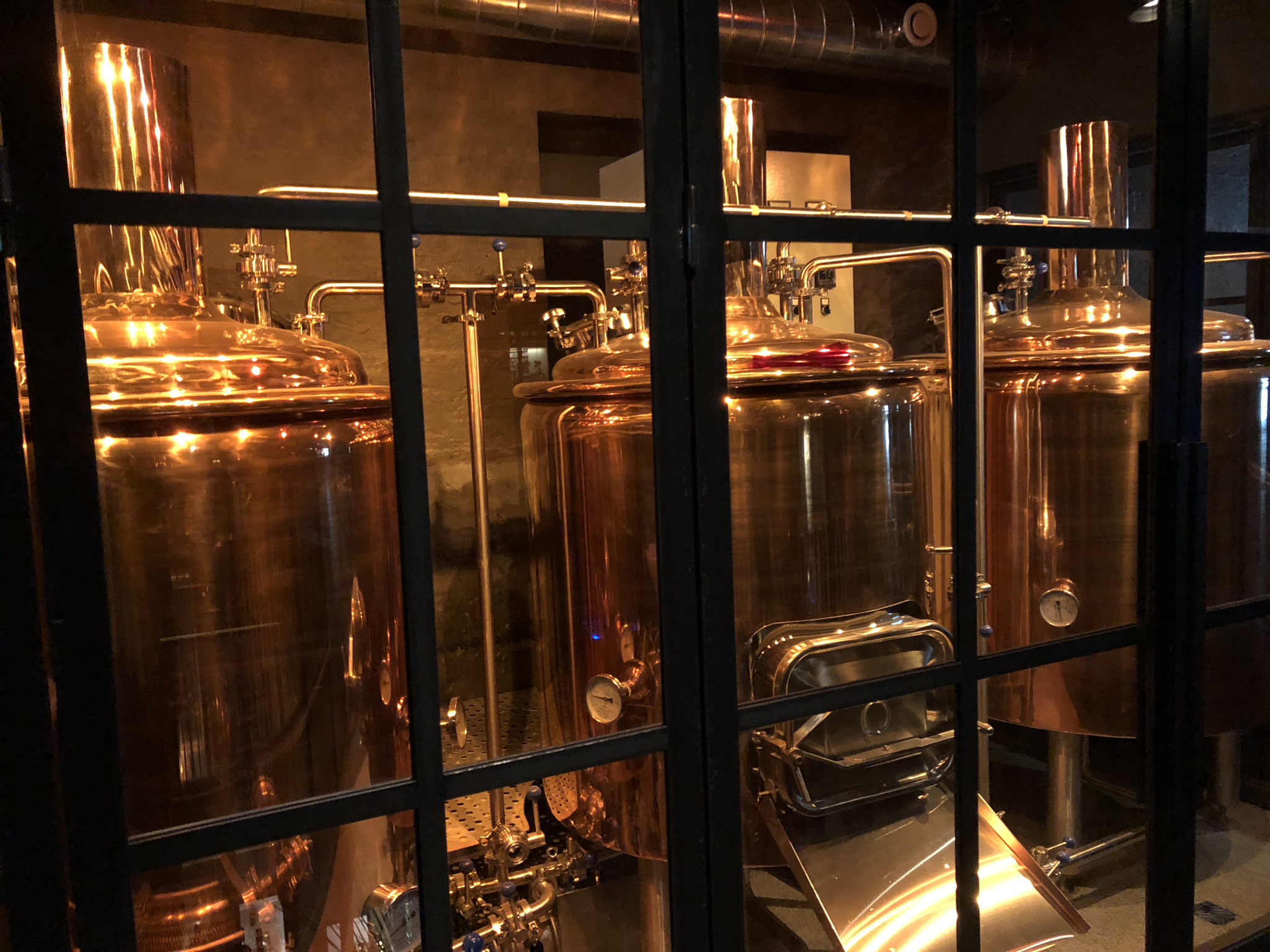 Copper brewhouse equipment photographed through glass