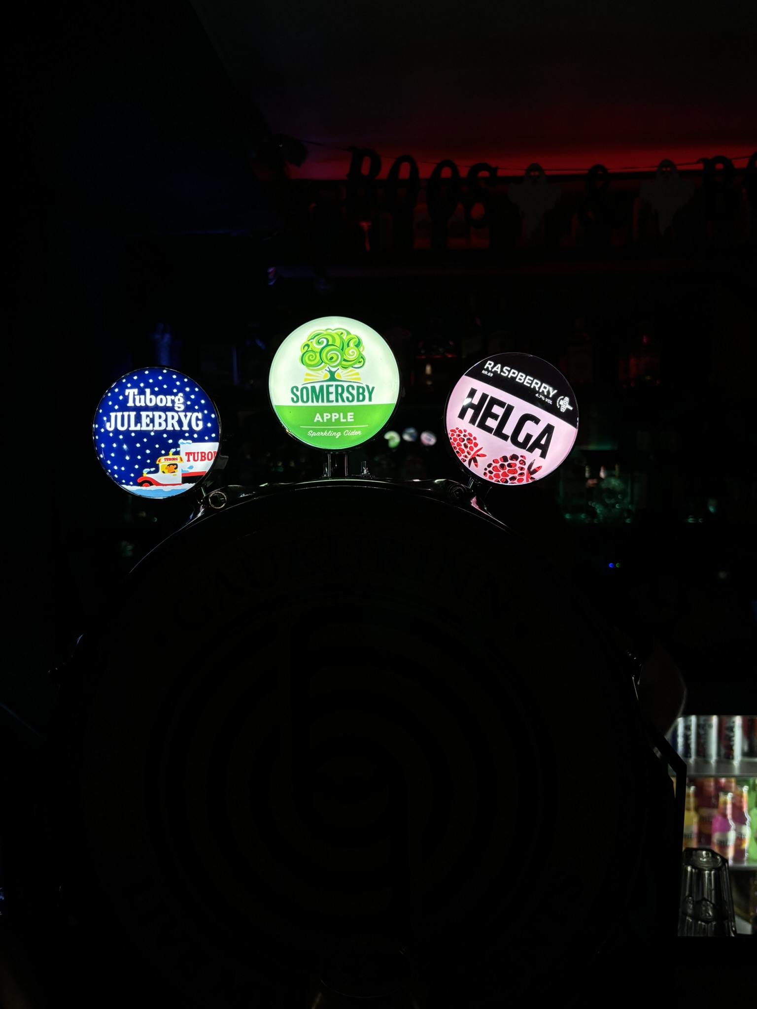 Illuminated international beer badges on a dark tap display